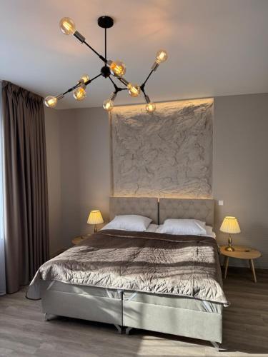 a bedroom with a large bed with a chandelier at DHARMA Stay Notaro apartamentai Self check-in in Telšiai