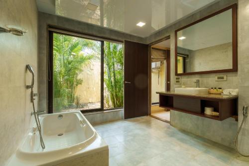 a bathroom with a tub and a sink and a mirror at Nehamrit Farmstays with Pool, Near Malshej Ghat in Murbād