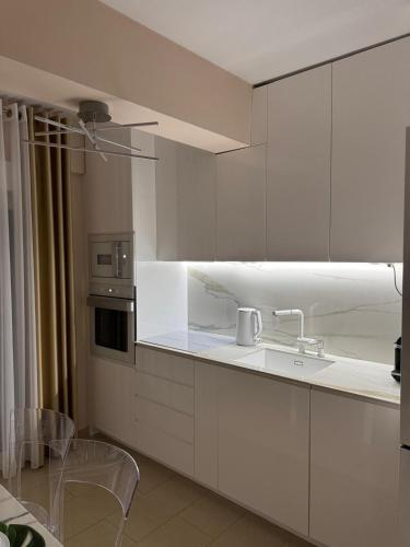 a kitchen with white cabinets and a sink at villa MeDITeRAN in Pefkohori