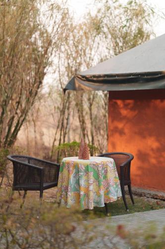 a table and two chairs with a table cloth on it at Nehamrit Farmstays with Pool, Near Malshej Ghat in Murbād
