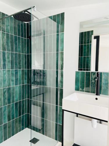 a bathroom with green tiled walls and a sink at La Maison au fond du jardin - proche centre ville in Le Mans