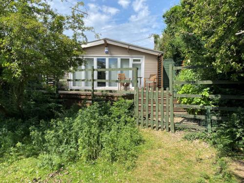 a small house with a porch and a fence at New Forest 2 bedroom Guest Suite & Hot Tub in Ibsley