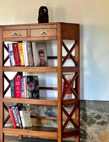 a wooden book shelf filled with books at Nehamrit Farmstays with Pool, Near Malshej Ghat in Murbād