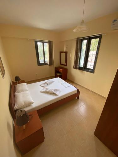 a bedroom with a bed and two windows at Βίλα Ηρώ in Riglia