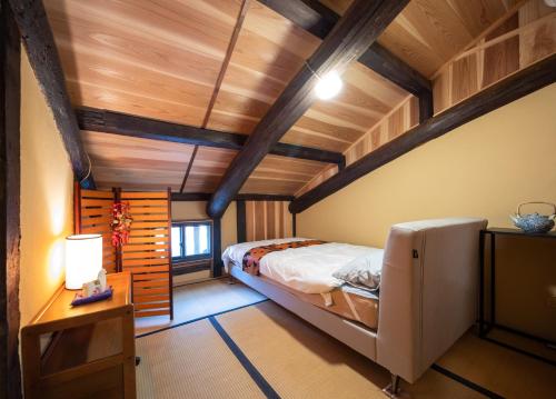a bedroom with a large bed and wooden ceilings at つなぐ古民家 in Kaizuka