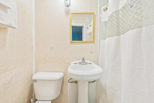 a white bathroom with a sink and a toilet at Flint Motel by OYO MI Near I-475 in Flint