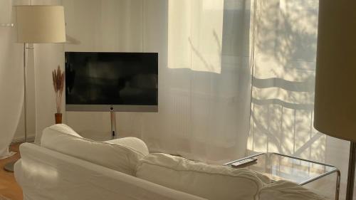 un salon avec un canapé blanc et une télévision dans l'établissement Designerwohnung mit malerischer Terrasse - Modern, Gemütlich & Zentral, à Hochheim am Main