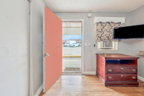 a door to a room with a desk and a television at Flint Motel by OYO MI Near I-475 in Flint