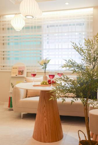 a table with two glasses of wine and a couch at 홍대ㆍ공항철도 STAY h #올리모델링#홍대입구역 도보9분#연트럴파크3분#짐보관# 6인#호텔침구#각방에어컨#무료와이파이#세탁건조기#교통최고 in Seoul