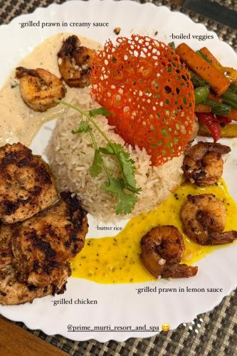 a plate of food with rice and meat and vegetables at PRIME MURTI RESORT and SPA in Chālsa Mahābāri