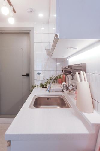 a kitchen with a sink in a white kitchen at 홍대ㆍ공항철도 STAY h #올리모델링#홍대입구역 도보9분#연트럴파크3분#짐보관# 6인#호텔침구#각방에어컨#무료와이파이#세탁건조기#교통최고 in Seoul