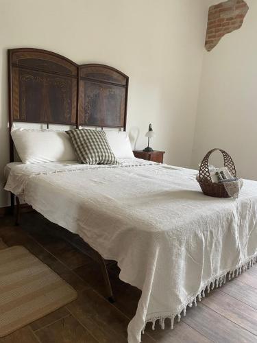 a bedroom with a large white bed with a basket on it at Tenuta Nissole in Rocchetta Tanaro