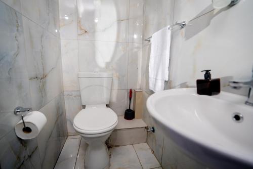 a white bathroom with a toilet and a sink at Boblodge in Cape Town