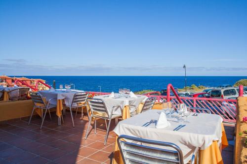 a row of tables and chairs with the ocean in the background at Apartamentos La Caleta in Los Cancajos