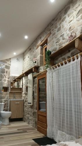La salle de bains est pourvue d'un rideau de douche et d'un mur en pierre. dans l'établissement Chambre d'hôte, à Meymac
