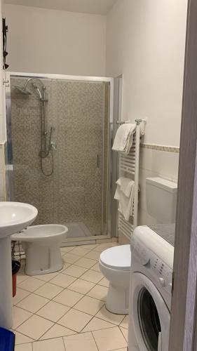 a bathroom with a shower toilet and a washing machine at Home Apollo in Giardini Naxos