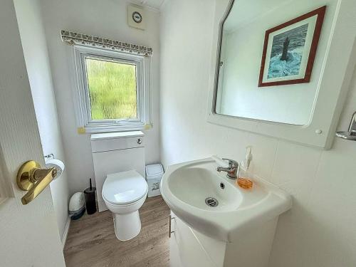 a white bathroom with a sink and a toilet at Pet Friendly, Luxury Lodge With Decking In Suffolk Near The Beach Ref 32108A in Lowestoft