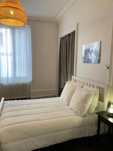 a bedroom with a bed with white sheets and pillows at Appartement #2 cœur de ville in Le Mans