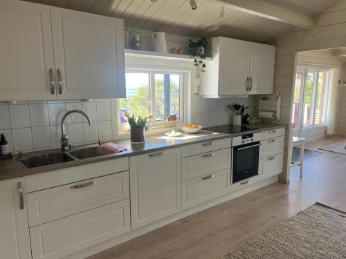 a kitchen with white cabinets and a sink at Welcome to Junibakken in Hofsøy
