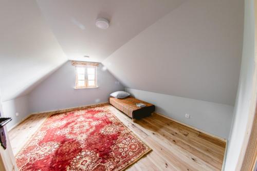 an attic room with a couch and a rug at Ostoja Poleska in Kołacze