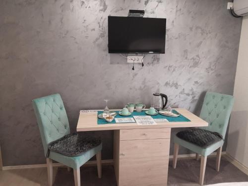 a table with two chairs and a television on a wall at Apartments Zejak in Mitrovići