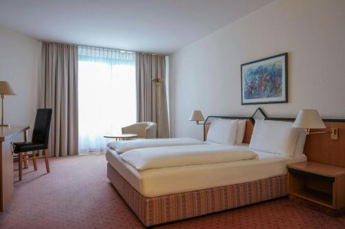 a hotel room with a large bed and a desk at FOUR Essen City Centre in Essen