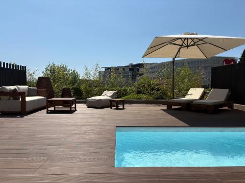 a patio with chairs and an umbrella and a pool at September Hotel Thessaloniki in Thessaloniki