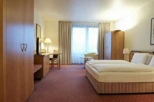 a hotel room with a bed and a desk at FOUR Essen City Centre in Essen
