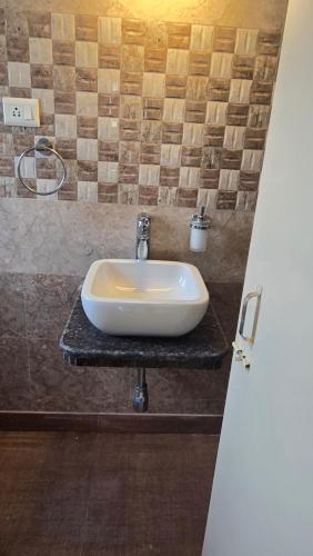 a white sink on a counter in a bathroom at Cozy apartment in jodhpur park, kolkata in Kolkata