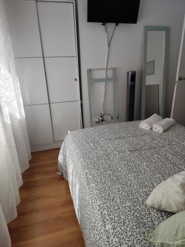 a bedroom with a bed with white sheets and a television at El apartamento de Fina in Gijón