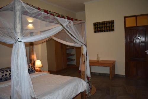a bedroom with a canopy bed and a table at Kili Kivuli in Msaranga