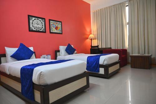 a hotel room with two beds and a red wall at The Kannelite in Jamshedpur