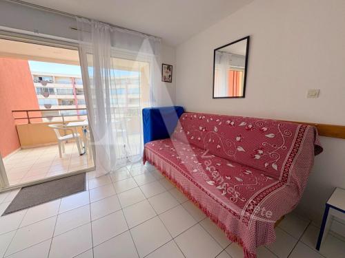 un salon avec un canapé rouge et un balcon dans l'établissement Terrasse vue piscine et apercu mer pour 4 personnes avec garage, à Sète