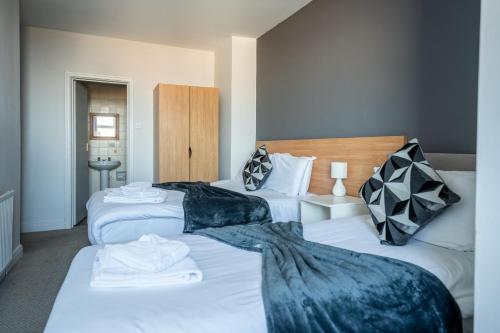 two beds in a hotel room with white sheets at The Strathmore Hotel in Morecambe