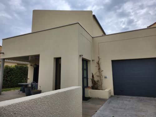 une maison blanche avec une porte de garage bleue dans l'établissement Annie-laure, à La Celle-sous-Gouzon