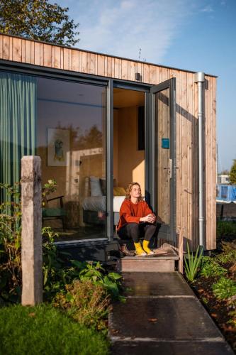 a woman sitting in the doorway of a tiny house at Zwier, de Vrijhaven in Vinkeveen
