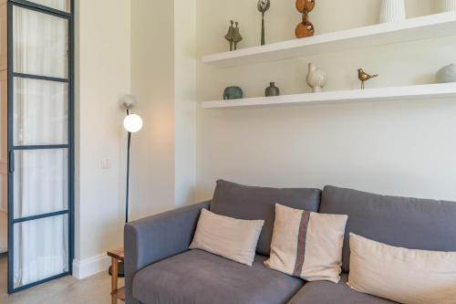 a living room with a gray couch and shelves at FLH Funchal Terrace Studio in Funchal