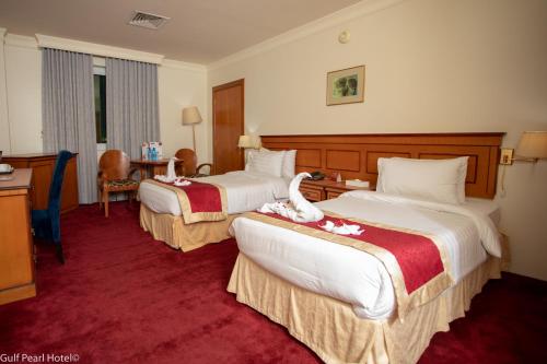 a hotel room with two beds with flowers on them at Gulf Pearl Hotel in Manama