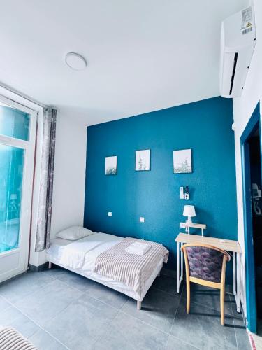 a bedroom with a blue wall with a bed and a desk at Emmanuel in Lourdes