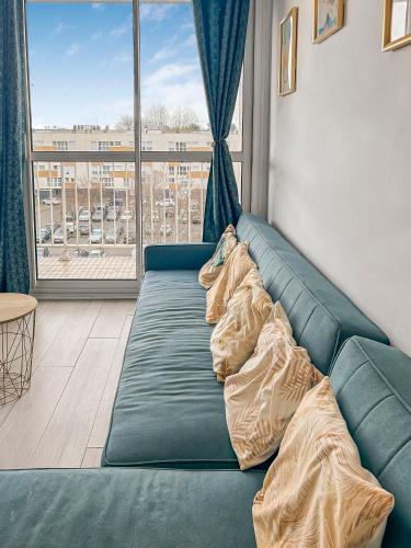- un canapé bleu dans une chambre avec une grande fenêtre dans l'établissement Lumineux avec balcon & confort familial, au Havre