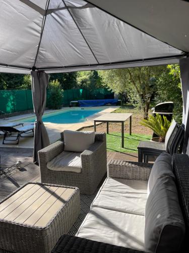 un patio avec deux chaises et un parasol dans l'établissement Havre de paix à St Paul en Forêt, à Saint-Paul-en-Forêt
