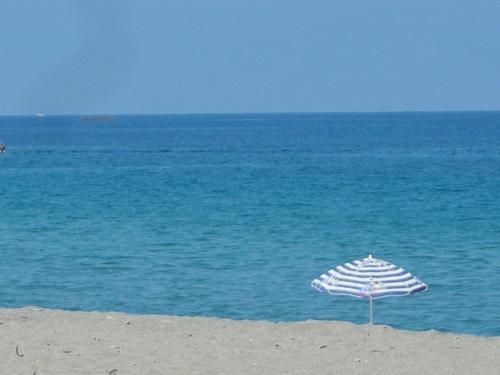 an umbrella sitting on the beach next to the ocean at Kalamos Due in Patti
