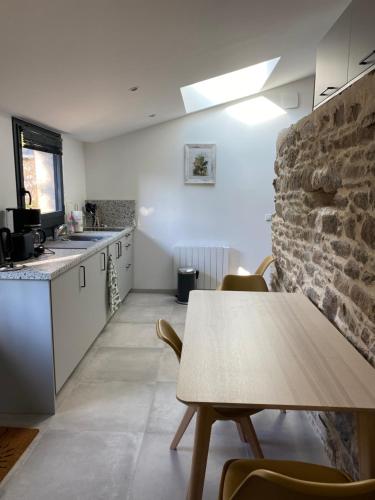 une cuisine avec une table et un mur en briques dans l'établissement Gîte à la campagne, à Malville