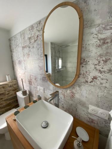 ein Badezimmer mit einem weißen Waschbecken und einem Spiegel in der Unterkunft Gîte à la campagne in Malville