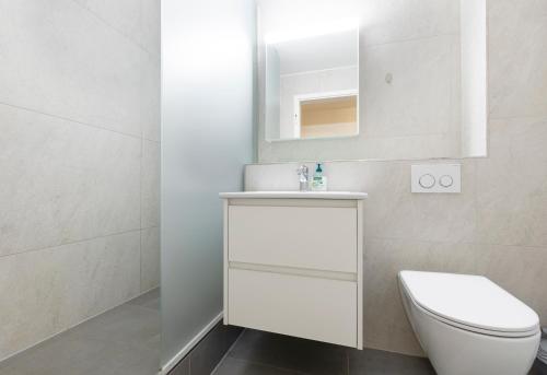 a white bathroom with a toilet and a sink at Center Appartement Interlaken in Interlaken