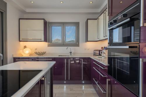 a kitchen with purple cabinets and a sink at Tranquil house in Kipséli