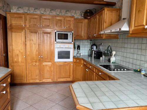 a kitchen with wooden cabinets and a stove top oven at ღ Ostaria - Maison Spacieuse, Piscine & Garage in La Couarde-sur-Mer