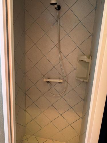 a shower with a hose attached to a tiled wall at ღ Ostaria - Maison Spacieuse, Piscine & Garage in La Couarde-sur-Mer