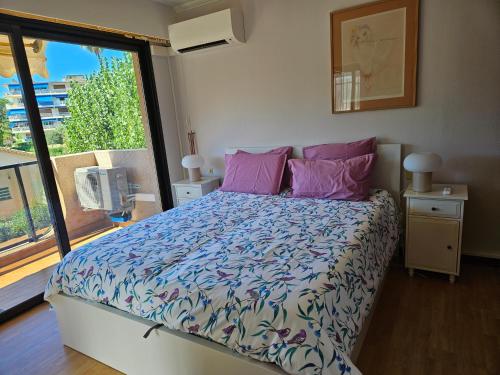 - une chambre avec un lit doté d'oreillers roses et d'une fenêtre dans l'établissement Vue mer beau 2 pieces, à Antibes