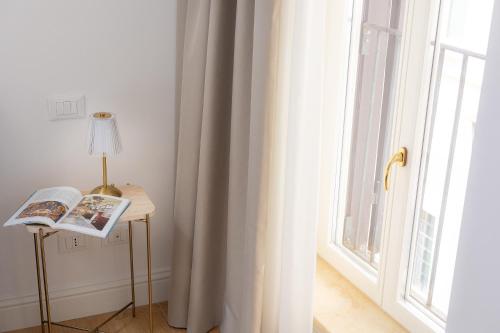 a room with a window and a table with a book at Amazing Via del Corso 277 Suites in Rome